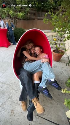 two people are sitting in a podoo shaped like a barrel with plants behind them