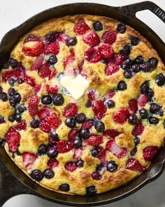 a skillet filled with berries and blueberries on top of a white countertop