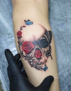 a woman's leg with a butterfly and roses tattoo on it