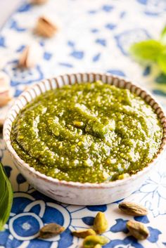 a bowl filled with pesto next to some nuts