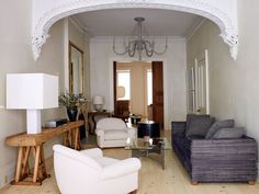 a living room filled with furniture and a chandelier hanging from the ceiling next to a doorway