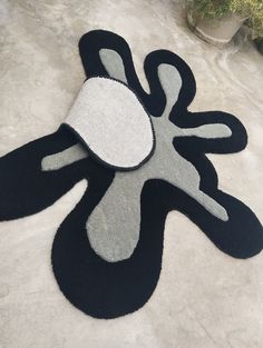 a black and white rug with an abstract design on the floor next to a potted plant