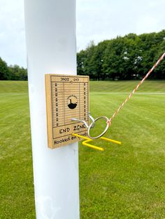 a white pole with a sign on it and some yellow poles in front of it