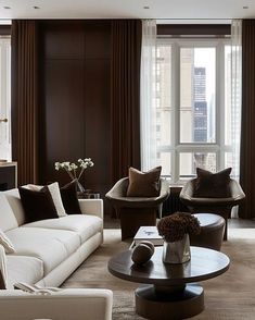 a living room filled with lots of furniture next to tall windows and curtains on the windowsill