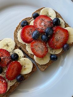 two pieces of bread with fruit on top and blueberries, bananas, and strawberries