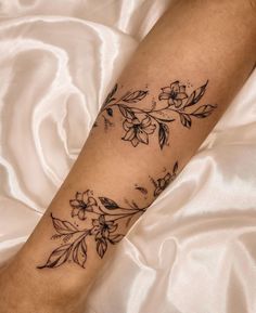 a woman's leg with flowers on it and a white sheet behind her,