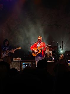 a man standing on top of a stage holding a guitar