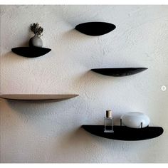 three black shelves on the wall with vases and other items sitting on top of them