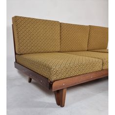 a couch that is made out of wood and has a patterned fabric on the back