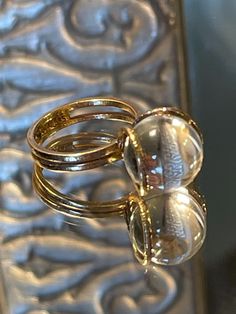 Rare 14k BRUTALIST MODERNIST POOLS OF LIGHT ROCK CRYSTAL GLASS ORB Ring!  in excellent condition! arrives in jewelry case and can be gifted immediately! crafted in solid 14k yellow gold - hallmarked and tested; came from Europe. weight approx 5.70g ; hand made solid gold - hammered like /organic surface - absolutely well made quality ring! orb is transparent and approx 12mm! GORGEOUS and RARE ring in excellent clean condition! smoke free environment; fast free USA priority insured shipping! for international please contact me. Elegant Clear Rings For Formal Occasions, Formal Oval Clear Rings, Unique Clear Round Rings, Modern Round Crystal Ring For Formal Occasions, Luxury Clear Rings For Anniversary, Luxury Clear Jewelry With Vs Clarity, Formal Clear Jewelry With Polished Finish, Formal Dome Ring With Vs Clarity, Unique Crystal Ring For Formal Events