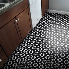 a kitchen with black and white tile flooring next to a sink, stove top oven and dishwasher