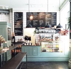 the interior of a coffee shop with menus on the wall and tables in front