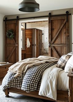 a bed with plaid blankets and pillows in a bedroom next to an open barn door