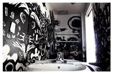 a bathroom with black and white wallpaper, sink and mirror in it's corner