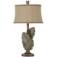 a table lamp with a beige shade on it and a green leaf design in the middle