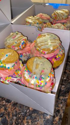 there are many cookies in the box with sprinkles and frosting on them