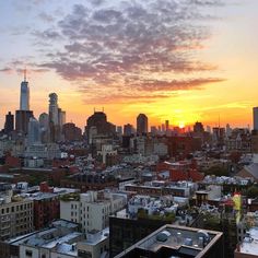 the sun is setting over a city with tall buildings and skyscrapers in the background