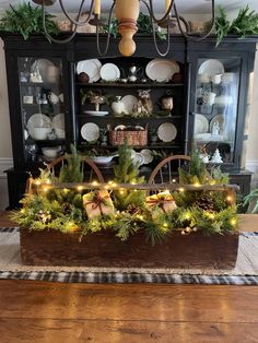 a dining room table decorated for christmas with lights and greenery on the top shelf