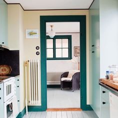 an open door leading to a kitchen with white cabinets and green trim on the doors