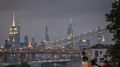 the city skyline is lit up at night, with people walking on the sidewalk below