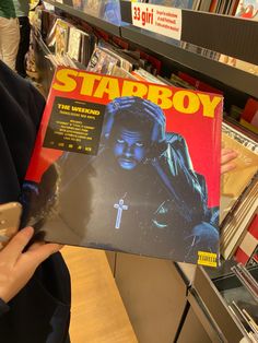 a person holding up a starboy album in a store