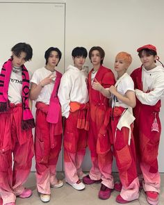 four men in red and pink outfits standing next to each other with their hands on their hips