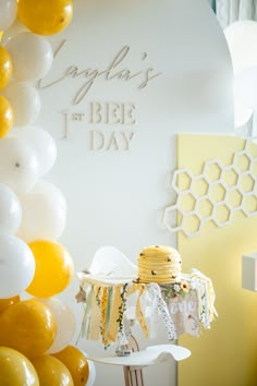 a table topped with yellow and white balloons next to a wall covered in honeycombs