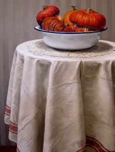 three pumpkins in a bowl on top of a white tablecloth with red trim