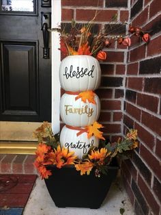 three pumpkins are stacked on top of each other in front of a brick wall