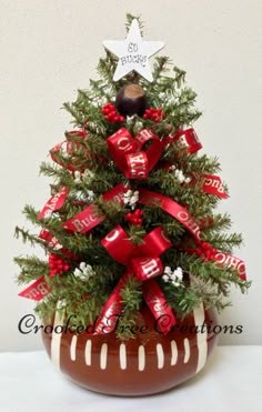 a small christmas tree in a pot with red bows