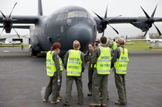 four women in yellow vests standing next to an airplane