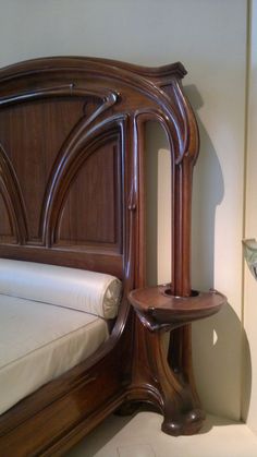 a wooden headboard and foot board on a bed with white sheets in a room