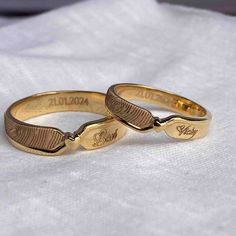 two gold wedding rings with engraved names on them