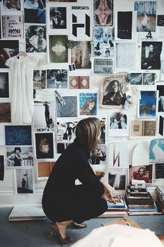 a woman sitting in front of a wall covered with pictures