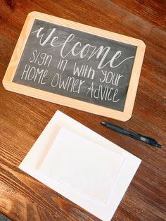 a welcome sign sitting on top of a wooden table next to a pen and paper