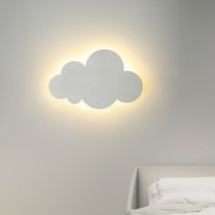 a white bed sitting under a cloud shaped light