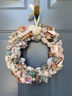 a wreath made out of seashells hangs on the front door