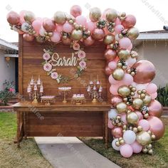 a pink and gold balloon arch is set up outside