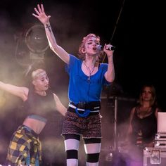 two women are performing on stage with their hands in the air and one woman is holding a microphone