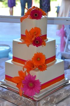 a three tiered cake with orange and pink flowers