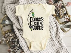 This Daddy's Fishing Buddy bodysuit/shirt is the perfect baby shower or birthday gift! All items are made to order--please check the estimated time or our shop announcement for shipping time frames.  Mountain & Field Co. bodysuits are a soft cotton/poly blend that baby and parents will love. They have a snap leg closure and envelope neckline.  I love being able to work on custom orders and help you create that perfect item that you have been searching for but can't seem to find exactly the way y Mountain Field, Fishing Baby, Baby Fish, Bodysuit Shirt, Perfect Baby Shower, Baby Outfit, Fishing Shirts, Kids Tops, Baby Shower Gift