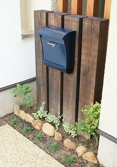 a blue mailbox sitting on the side of a building next to a planter