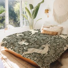 a bed in a bedroom next to a window with plants on the wall and pillows