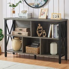 a wooden shelf with books and vases on it in front of a white wall