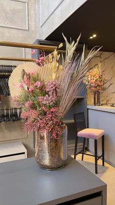 a vase filled with lots of flowers on top of a table next to a chair