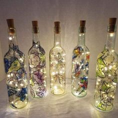 lighted wine bottles with flowers and fairy lights in them