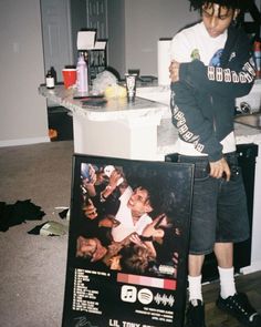 a man standing next to a poster in a kitchen