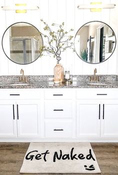 a bathroom with two sinks and mirrors on the wall next to a rug that says get naked