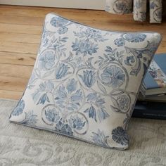 a blue and white pillow sitting on top of a wooden floor next to two books