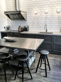 a kitchen with black cabinets and stools next to a stove top oven over an island